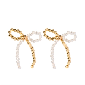 Detailed view of bow earrings with gold beads and white faux pearls in an elegant design