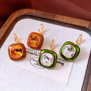 Detailed macro view of vintage square amber and emerald crystal earrings on wood