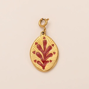 Detail of 18K gold plated horseshoe pendant with red enamel plant pattern and spring clasp