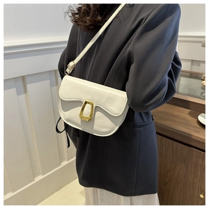 Close-up of white vintage PU leather saddle bag with gold buckle and adjustable strap