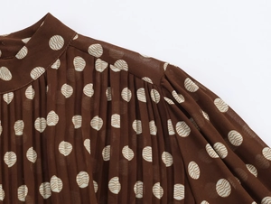 Detail showing high neck and pleated design of the brown polka dot elegant maxi dress