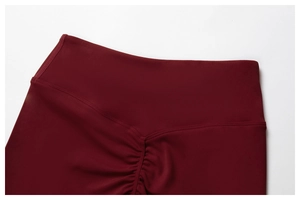 Makro-Detail der High-Waist-Scrunch-Naht an dunkelroten Yoga-Shorts für den Push-up-Effekt