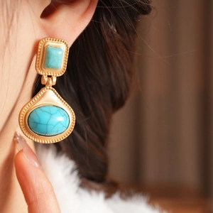 Close-up of vintage resin earrings with turquoise stones on a gold metal base