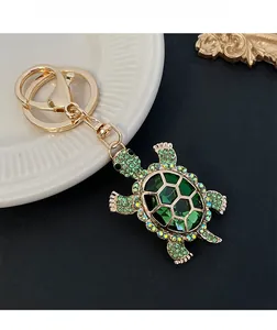 Detailed shot of a turtle keychain with green crystals and gold base on a ceramic tray