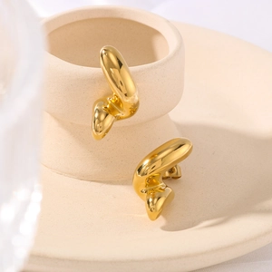 Artistic gold twisted geometric earrings in stainless steel on a ceramic tray