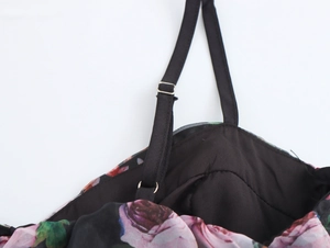 Detail of adjustable black straps with metal buckles on floral organza dress