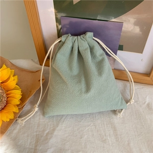 Mint green cotton linen drawstring storage bag on a rustic home decor background