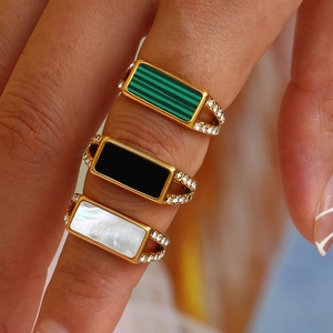 Detailed view of three gold rings featuring diamonds with malachite, onyx, and mother of pearl