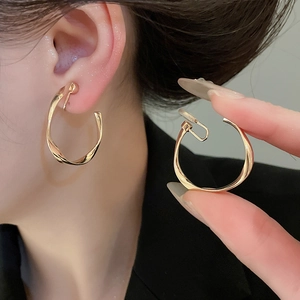 Close-up of golden twisted hoop earring showing sleek metallic texture and modern design