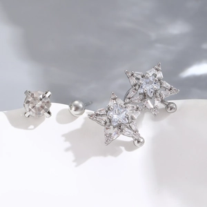 Set of three silver zircon star earrings and single stud on a minimalist wave base