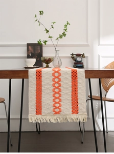 Detail view of woven table runner with orange geometric patterns and tassel trim