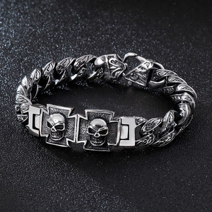 Dettaglio macro di un bracciale vintage in acciaio con teschio gotico, croce e incisioni fini