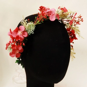 Detail of a floral headband with red and pink silk flowers on a black mannequin head
