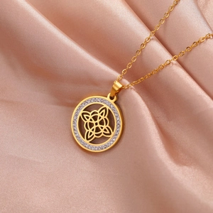 Gros plan d'un collier pendentif nœud celtique doré avec zircons sur fond de soie rose