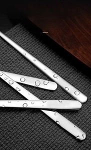 Detail of water droplets on a one-piece stainless steel spoon showing smooth finish