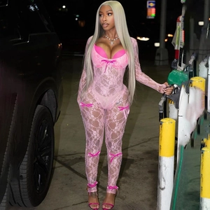 Detailed texture of pink lace jumpsuit with delicate bow decorations in soft focus