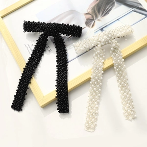 Detail of handcrafted beaded hair clips in black and white pearl finishes on a wooden frame
