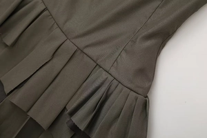 Detailed close-up of olive green pleated fabric texture and stitching on the slip dress