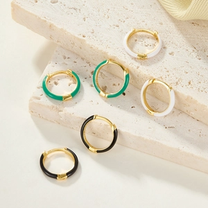 Detail of colorful enamel S925 silver hoop earrings in white, emerald and black