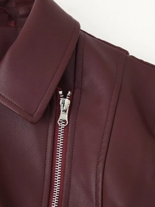 Detail der weinroten PU-Lederjacke mit Reverskragen und silberner Metall-Reißverschlusstextur