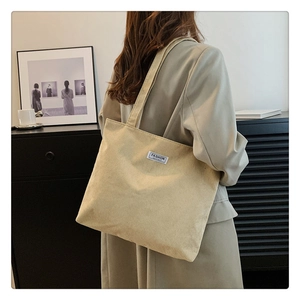 Detail view of beige corduroy tote bag showing ribbed texture and fashion logo patch