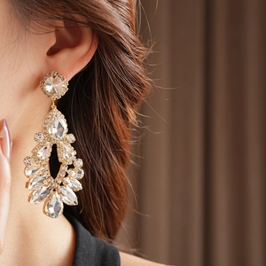 Close-up of sparkling crystal drop earrings with rhinestone tassels worn by a model