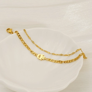 Gold double-layer chain bracelet featuring a Hamsa Hand charm on a shell plate