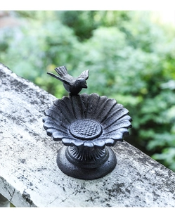 Close-up of a rustic cast iron sunflower bird feeder with decorative bird sculpture