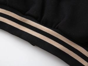 Detail of black baseball jacket with khaki double-striped elastic ribbed cuffs