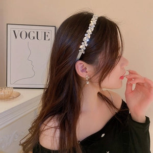 Close-up of sparkling rhinestone headband and flower earrings on a model in warm light