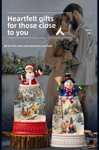 Close-up of Santa Claus and snowman snow globes with festive holiday couple background