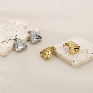 Macro shot of irregular triangle earrings with ripple texture in gold and silver finish