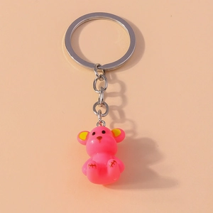 Detailed view of a pink resin teddy bear keychain with metal ring on yellow background