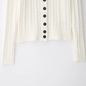 Chic white cable knit cardigan featuring black buttons and ribbed hem texture