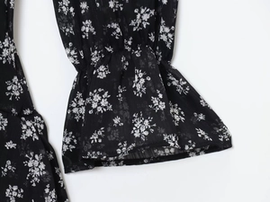 Detail van bloemenprint chiffon jurk met uitlopende manchetten en lichte stoftextuur