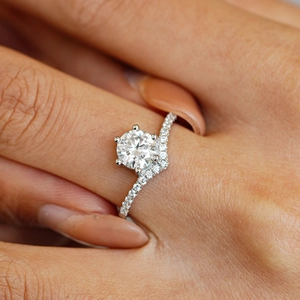 Classic six-prong Moissanite ring with a wavy micro-paved silver band on finger