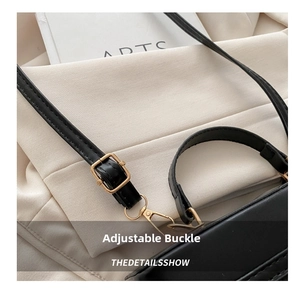 Close-up of adjustable shoulder strap with gold metal buckle on black crossbody bag