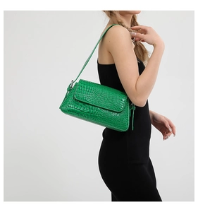 Detail view of green crocodile pattern texture on a stylish women's shoulder bag