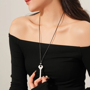 Gros plan sur un collier pendentif clé en argent avec une chaîne en cuir tressé noir