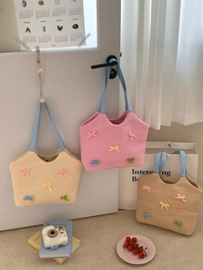 Close-up of woven straw tote bags featuring colorful 3D bowknot decorations and blue handles