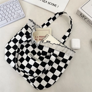 Close-up of checkered canvas tote bag with lace trim and daily items organized inside