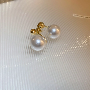 Macro detail of elegant gold plated pearl earrings featuring a sleek minimalist arc design