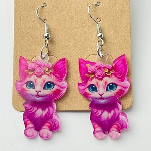 Close-up of pink acrylic cat earrings with rose decor on a brown card display
