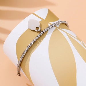Detail of silver beaded bracelet with heart charm on white decorative display stand