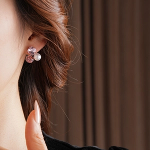 Close-up of elegant triangle cluster earrings with pink crystals and a white pearl