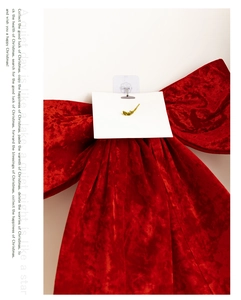 Detail of a large red velvet bow hanging on a white wall with a decorative blank gift card