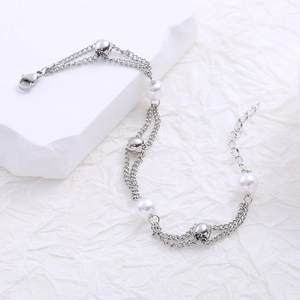 Close-up of double-layer silver bracelet with white pearls and beads on stone base