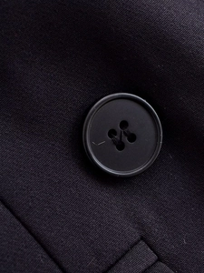 Detailed macro view of a four-hole round button on textured navy woven fabric