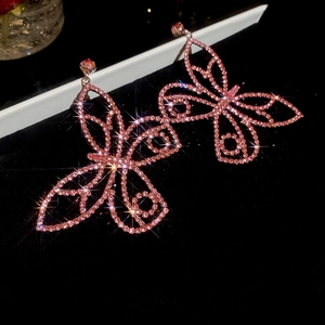 Détail de boucles d'oreilles papillon roses serties de strass brillants et glands