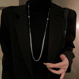 Close-up of elegant multilayered silver pearl necklace on a black turtleneck sweater